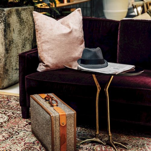 A cozy outdoor setup with a pink cushion on a chair, a small wooden side table, and a laptop or device on the table.