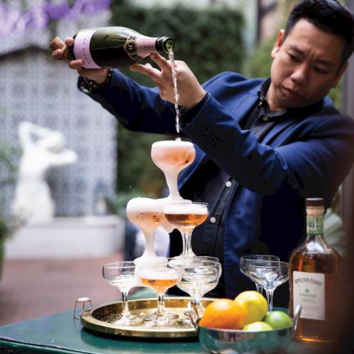 A chef is pouring a tall, multi-tiered dessert or stacking dish, with dramatic plating and fruit accents; action-packed kitchen scene.