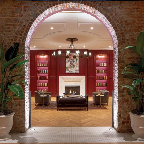 Entrance to a hotel or building lobby with a red door, archway, plants, and warm lights.