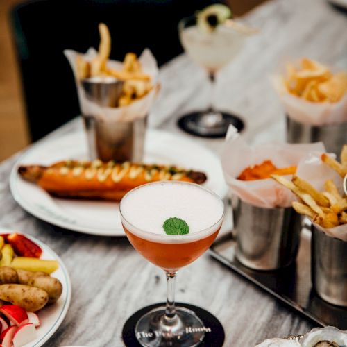 A stylish brunch spread with coffee, cocktails, pastries, small bites, and a few savory dishes arranged on a white table, inviting and elegant.