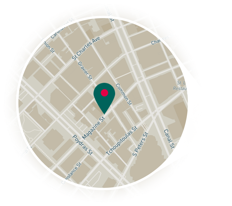 A circular map with a beige street grid, a teal pin marker at the center, and a white page curl at the edge.